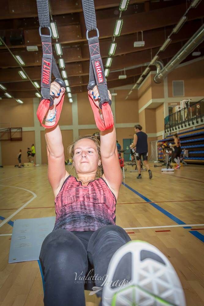 Una donna sta facendo esercizi su un trainer a sospensione in una palestra.