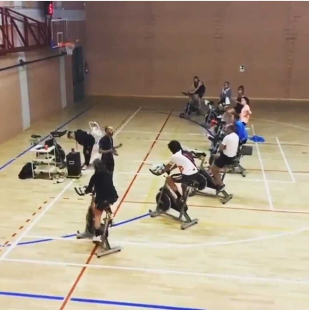 Un gruppo di persone sta pedalando su cyclette in una palestra