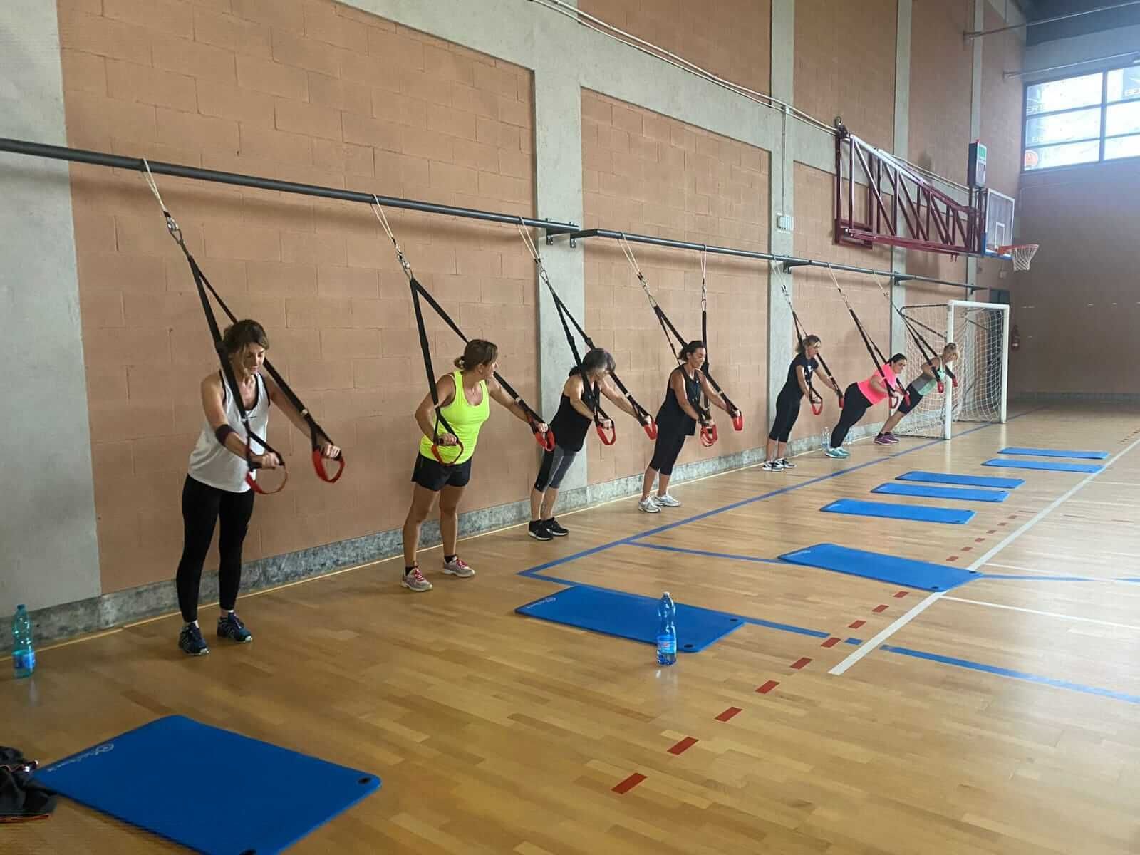 Un gruppo di donne sta facendo esercizi trx in una palestra.
