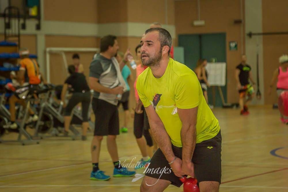 Un uomo sta sollevando un kettlebell in una palestra.