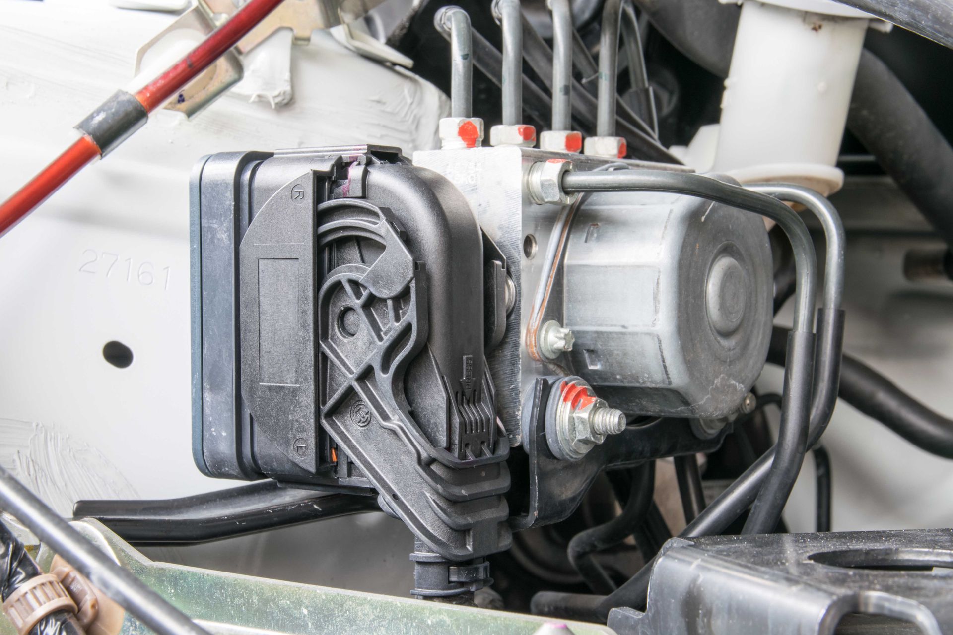 Module ABS dans le compartiment moteur d'une voiture, avec la tuyauterie et le câblage associés.