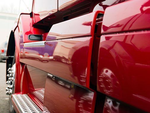 Gros plan sur la cabine rouge d'un semi-remorque, avec une peinture brillante et réfléchissante et des accents chromés.