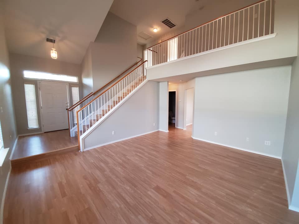 An empty living room with hardwood floors and stairs in a house.
