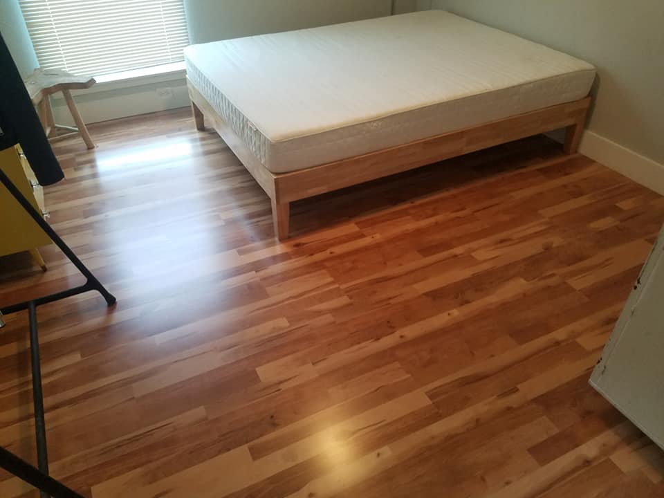 A bed is sitting on a wooden floor in a room.