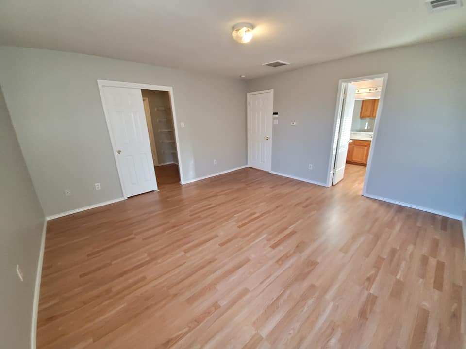 An empty room with hardwood floors and gray walls.