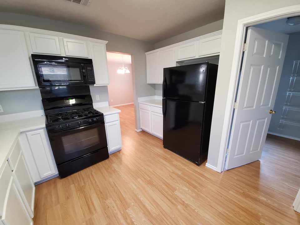 A kitchen with a black refrigerator , black stove , and white cabinets.