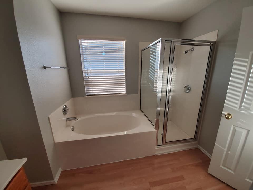 A bathroom with a tub , shower and window.
