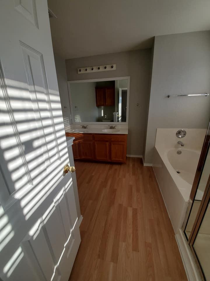 A bathroom with a tub , sink , mirror and blinds.