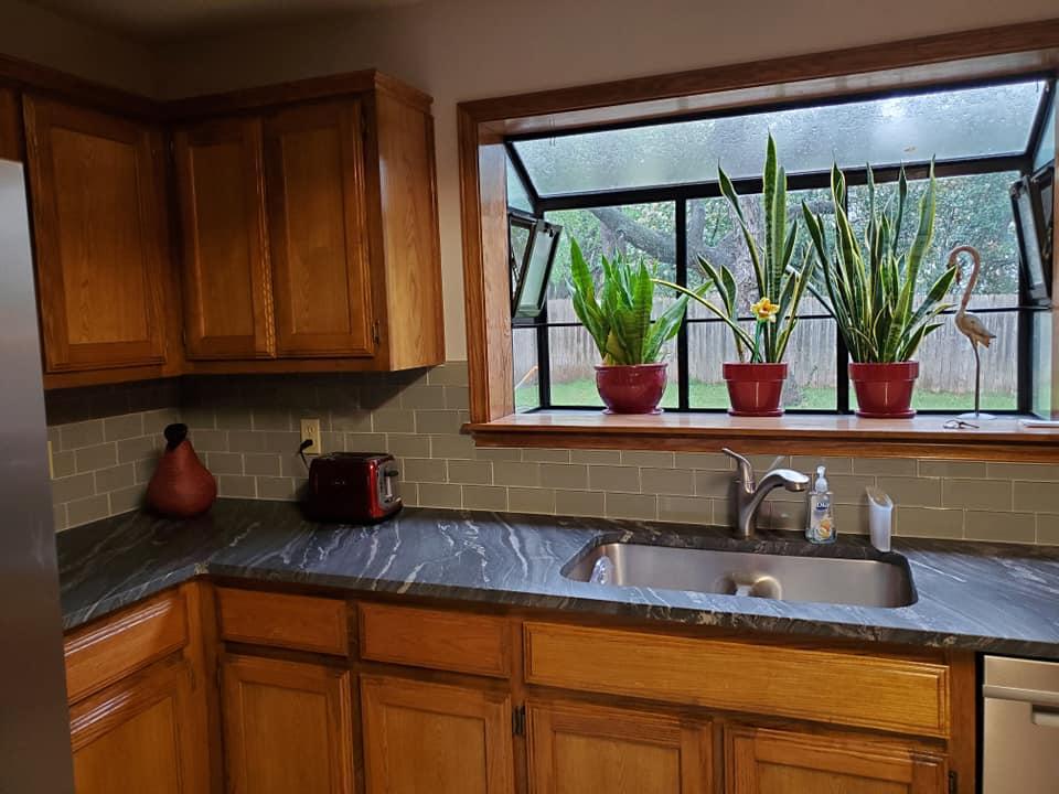 A kitchen with a sink and a window with potted plants on it.
