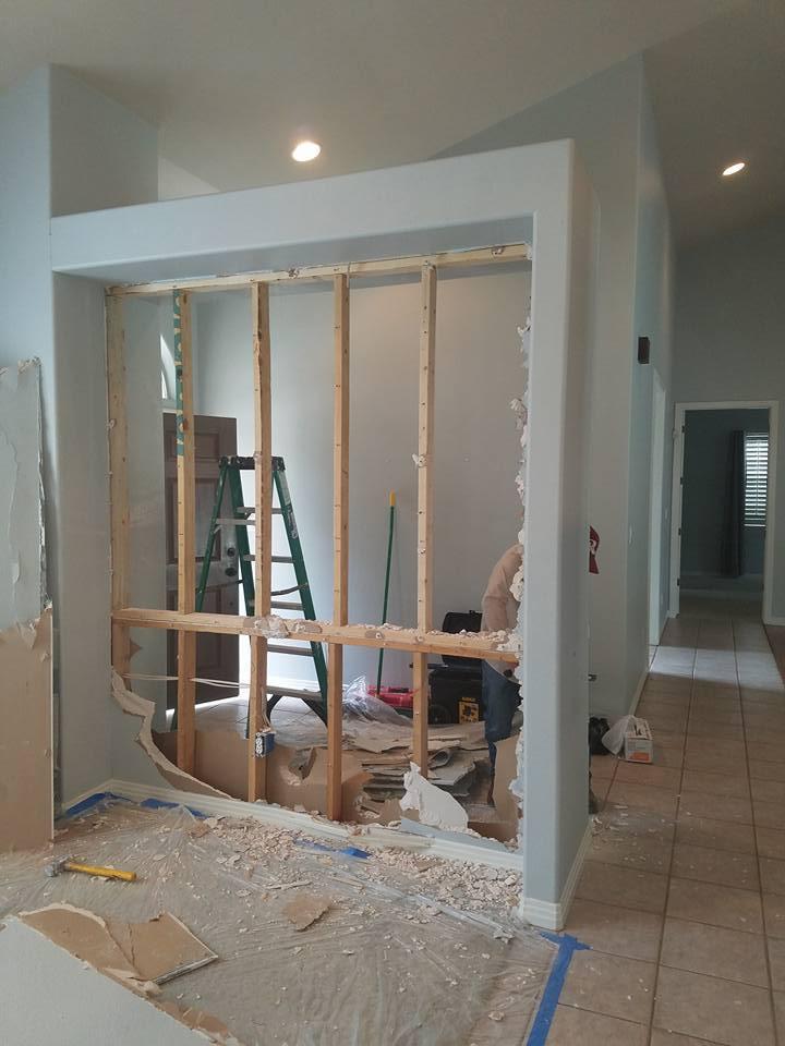 A man is working on a wall in a room.