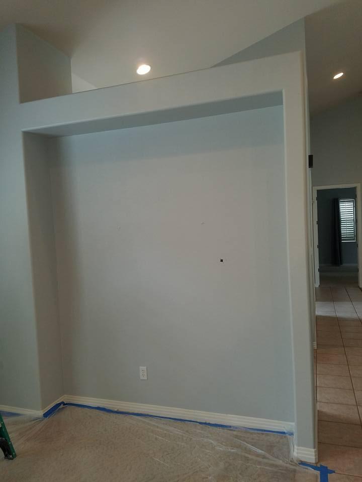 A living room with a gray wall and a blue tape on the floor.