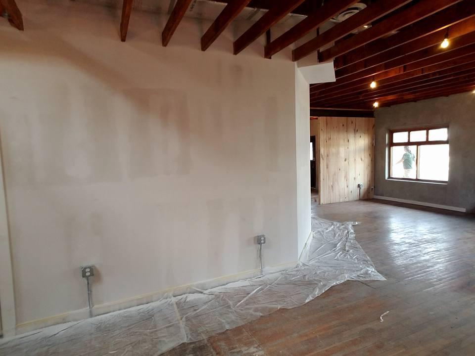 An empty room with a wooden floor and a white wall.