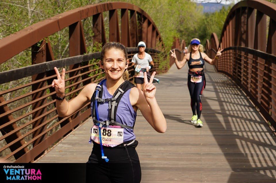 Runner throwing up peace signs running across a bridge at the Ventura Marathon