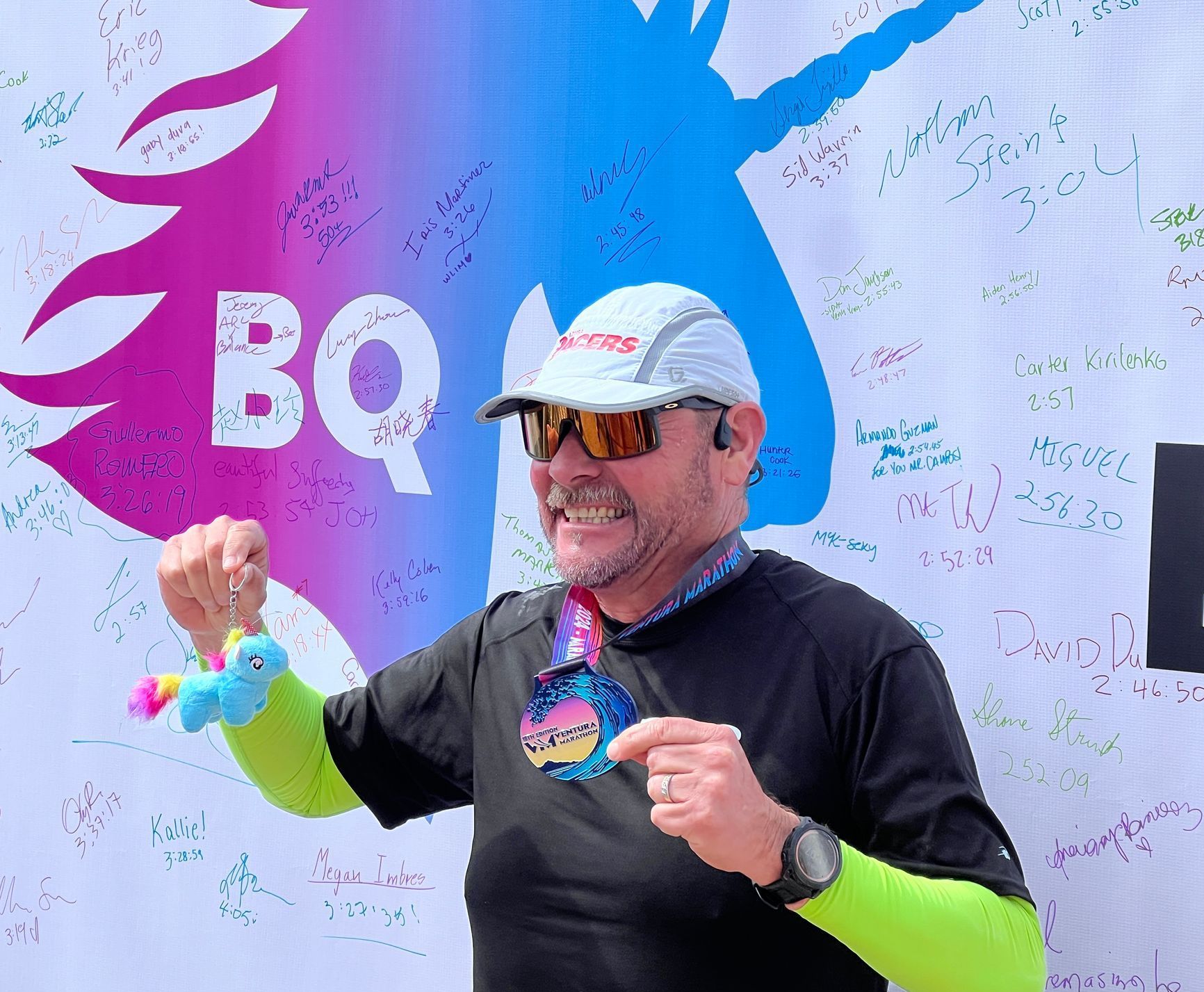 Runner showing off his BQ Unicorn in front of the BQ photo backdrop.