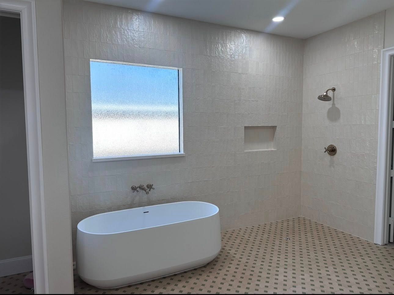 A modern bathroom featuring a white freestanding tub, a square window, a wall-mounted faucet, and a shower area.