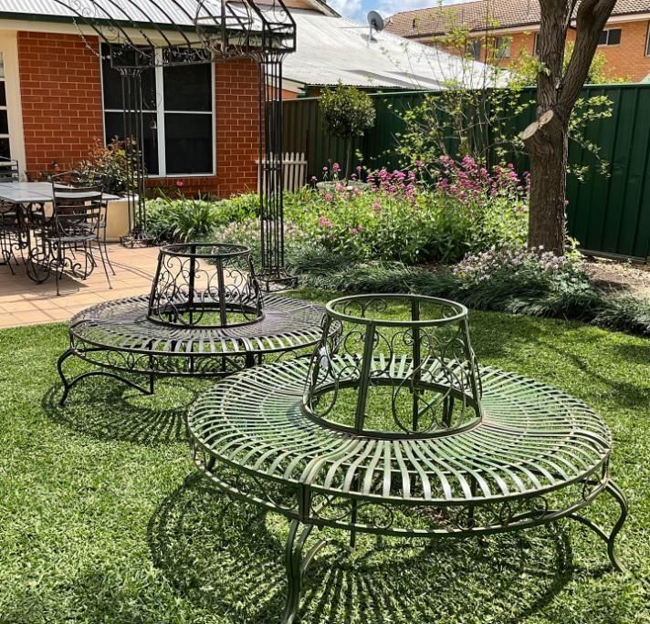 Two Wrought Iron Benches Are Sitting In The Grass In A Backyard — Magnolia Nursery In Dubbo, NSW