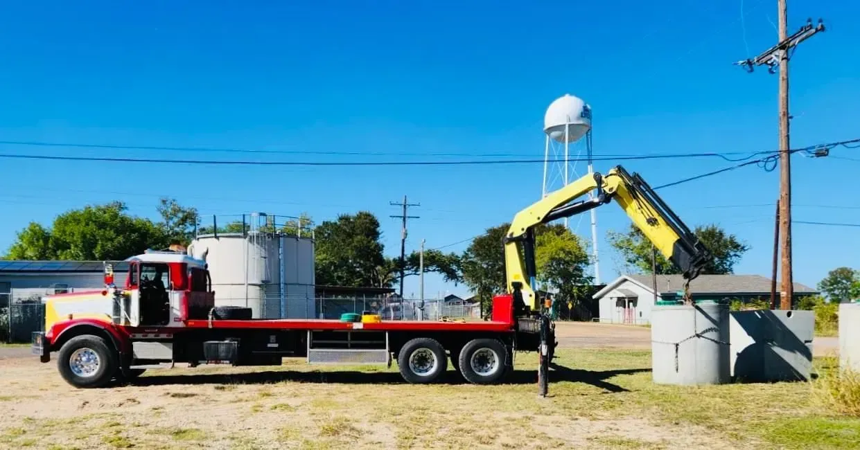 A truck with a crane on the back is parked in a field.