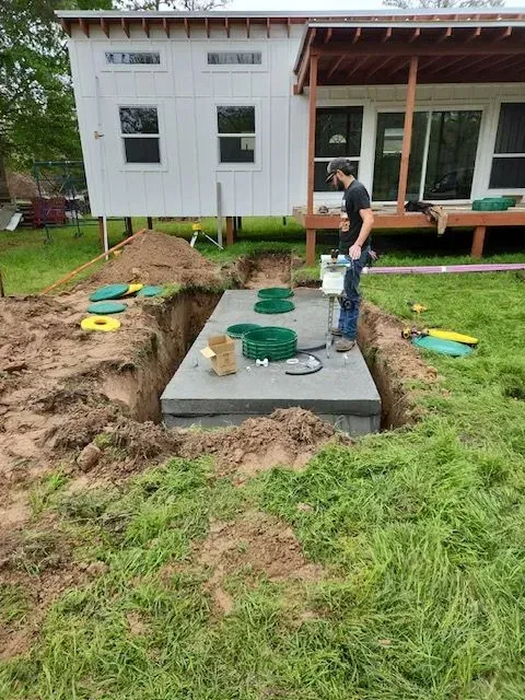 A man is standing in a hole in the ground in front of a house.