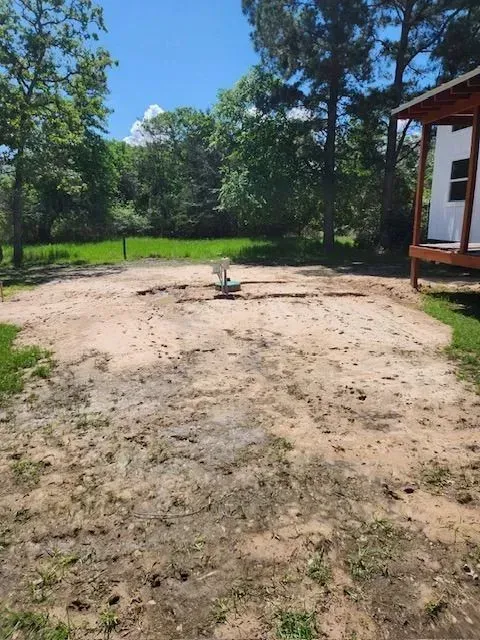 A dirt field with a house in the background