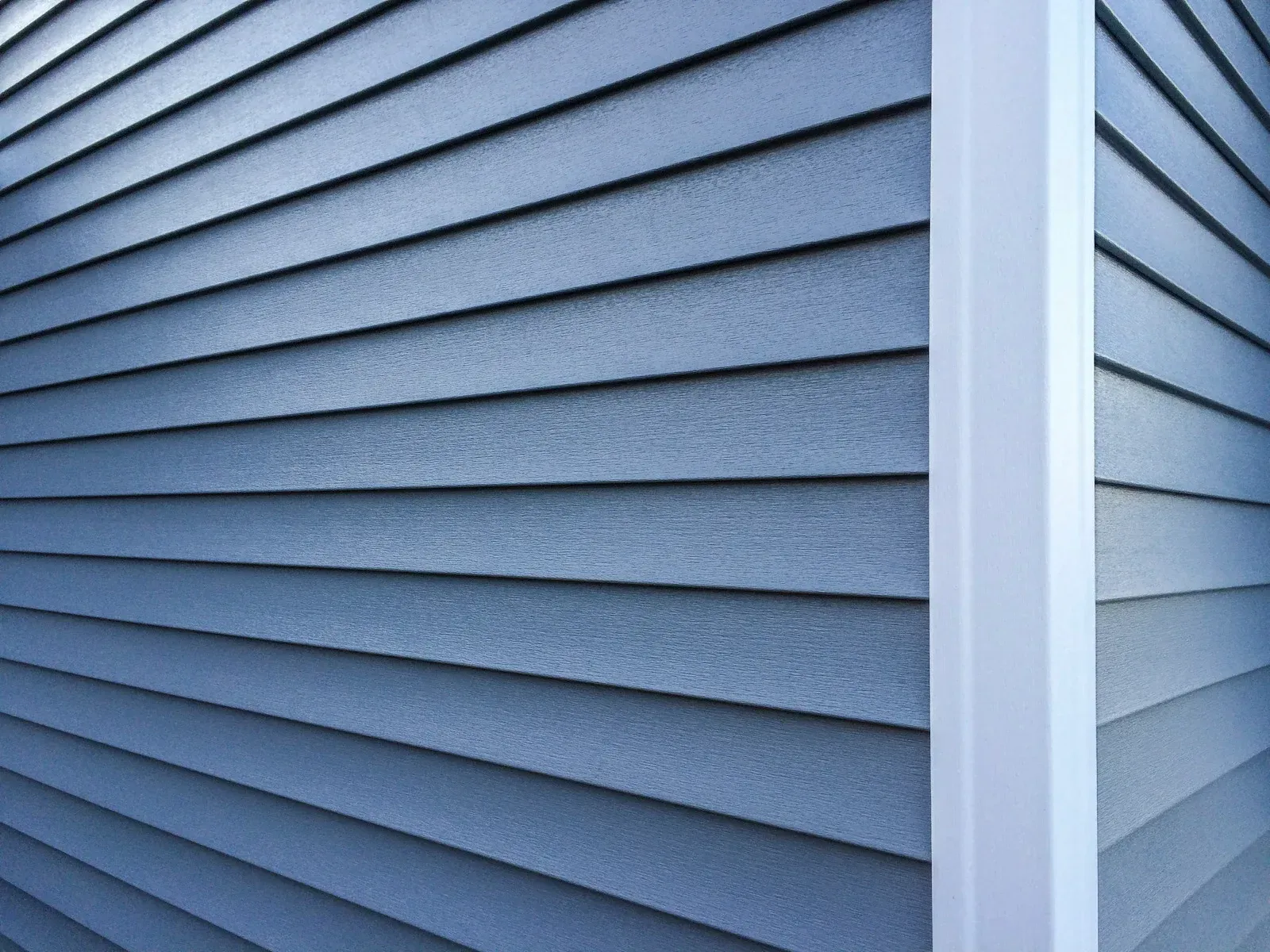A close up of a blue siding on a house with a white trim