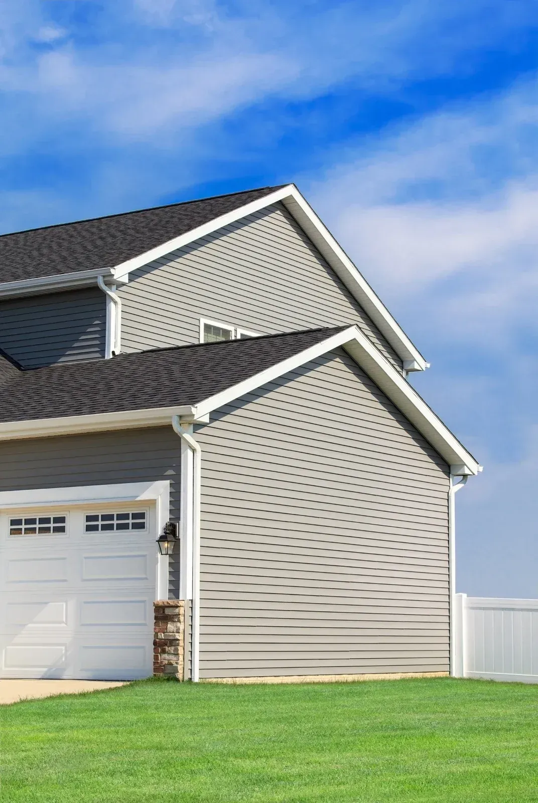 A house with a garage and a blue sky in the background.