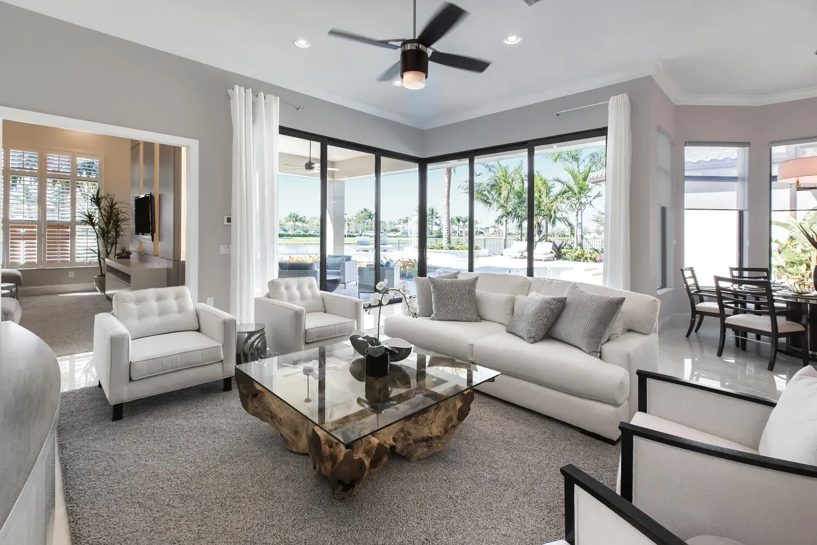 A living room with a couch , chairs , a coffee table and a ceiling fan.