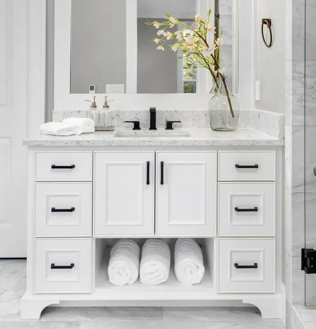 A bathroom vanity with a sink , mirror and towels.