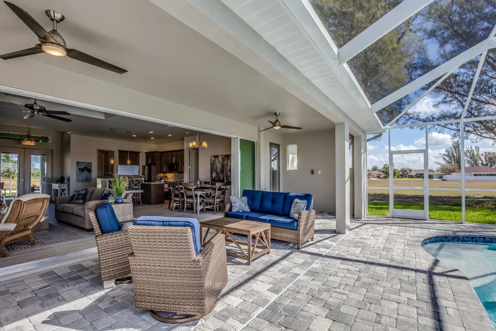 A living room with a couch , chairs , and a ceiling fan next to a pool.