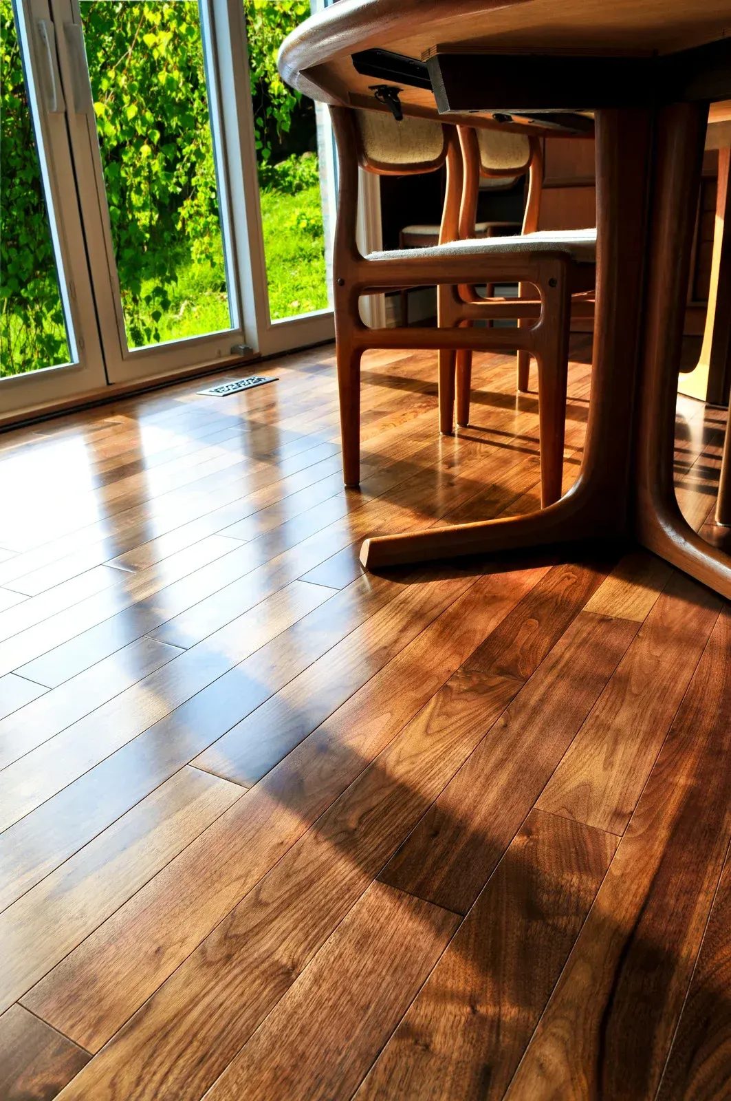 A wooden floor with a table and chairs in a room.