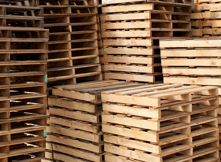 A pile of wooden pallets are stacked on top of each other.