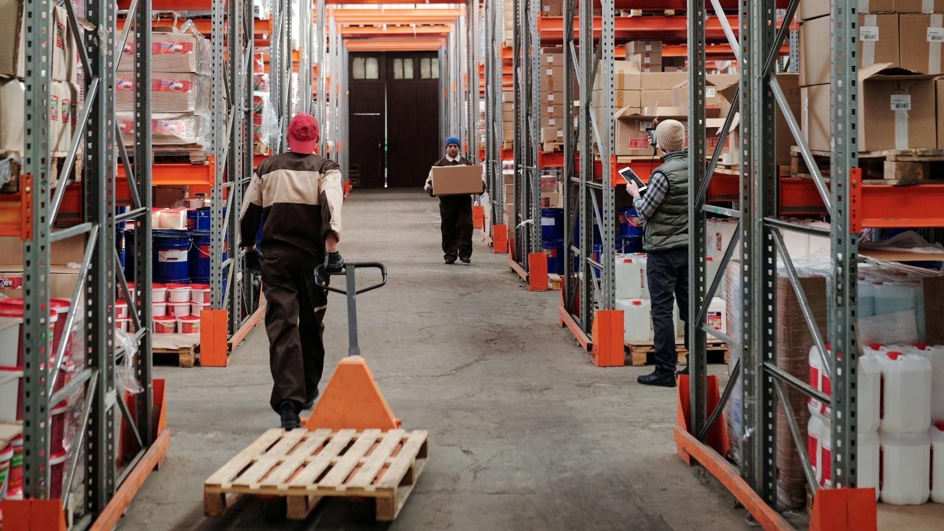 A man is pushing a pallet in a warehouse.