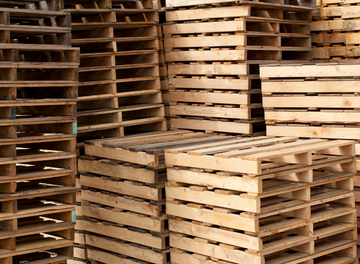 A pile of wooden pallets are stacked on top of each other.