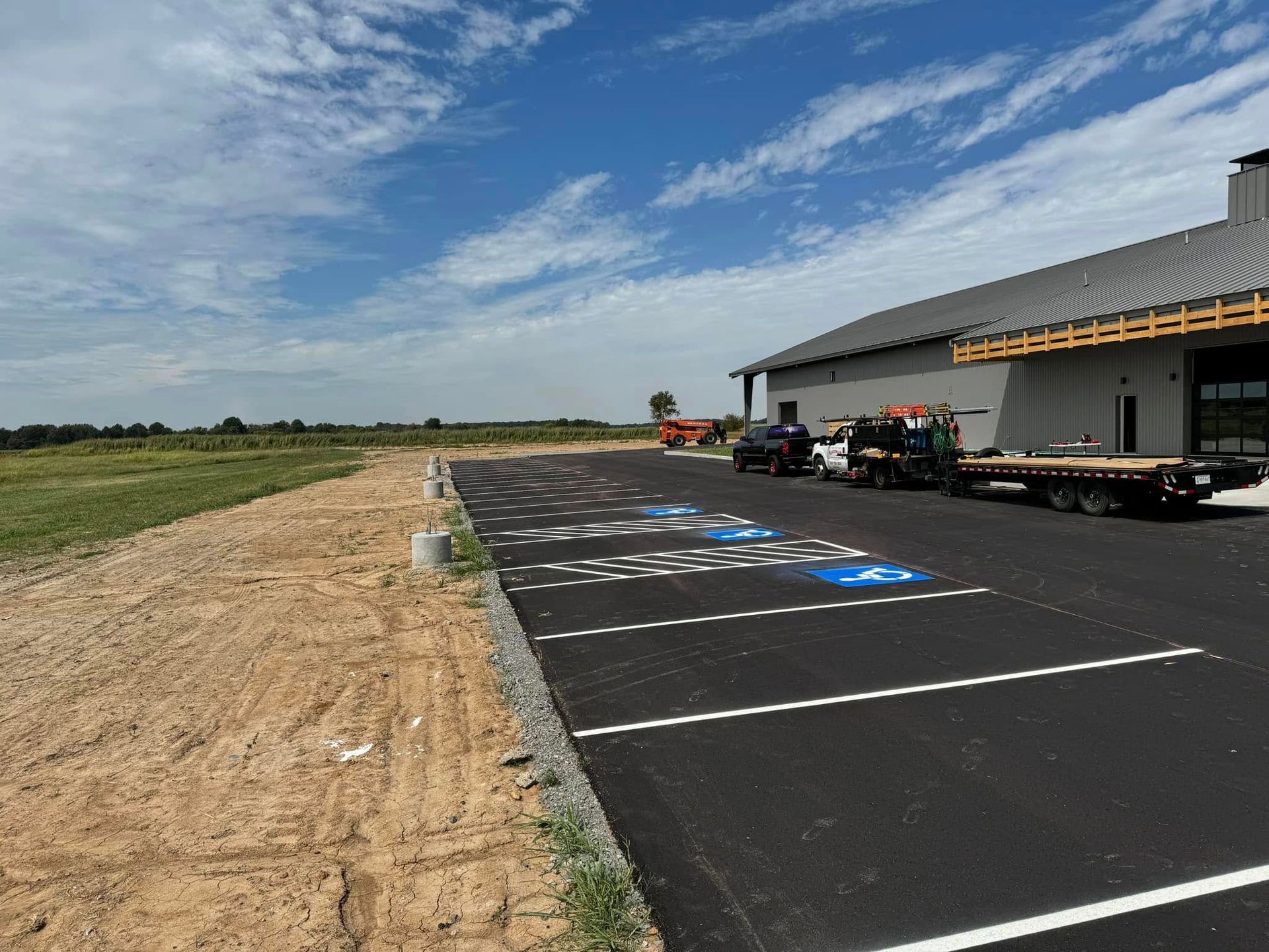 Newly paved parking lot with handicap spaces in front of a modern building under a blue sky.