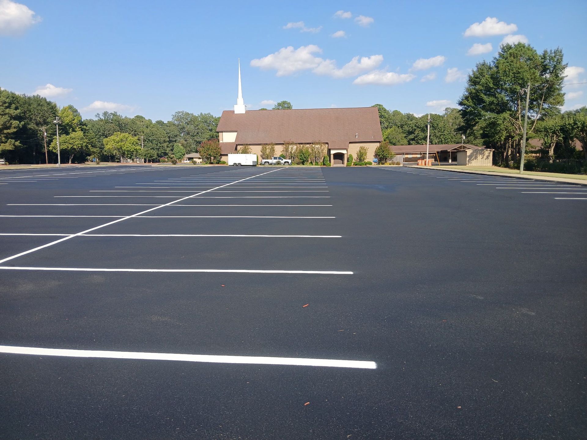 Empty asphalt parking lot in front of a church building, blue sky overhead.