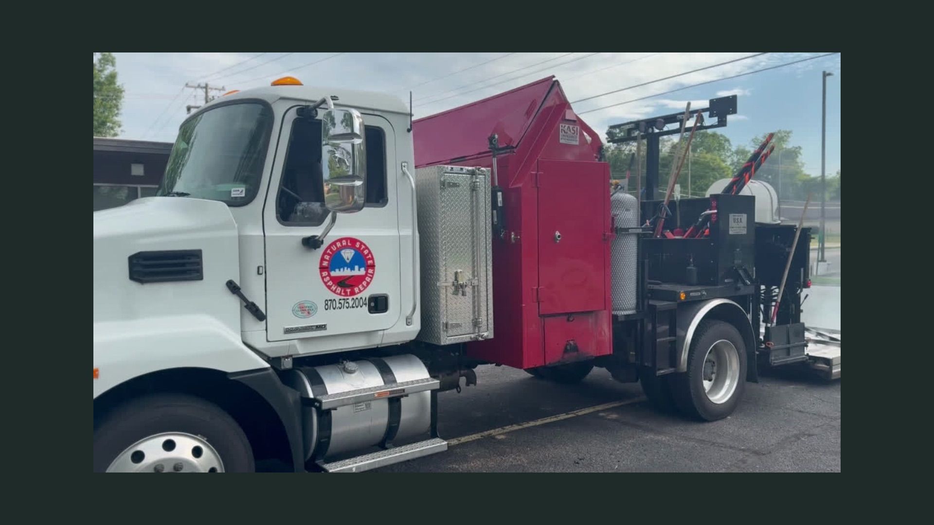 White truck with red equipment, parked outdoors, possibly for road work.