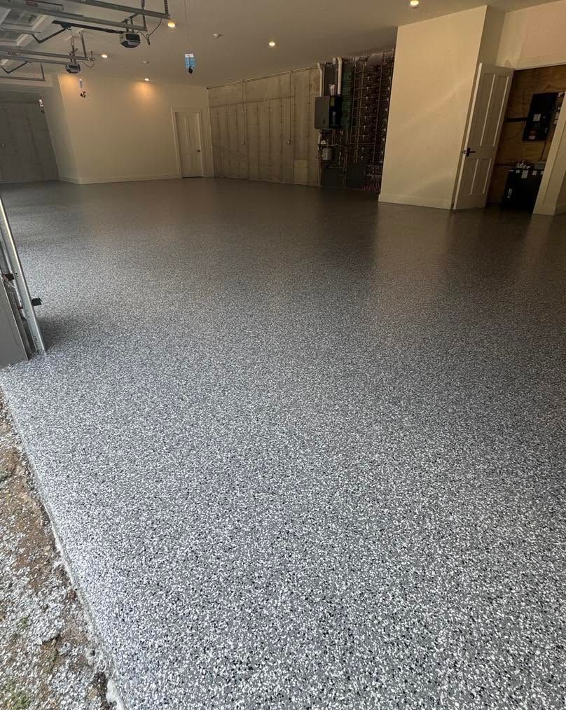 Empty indoor showroom with speckled gray epoxy floor and white walls, viewed from one corner
