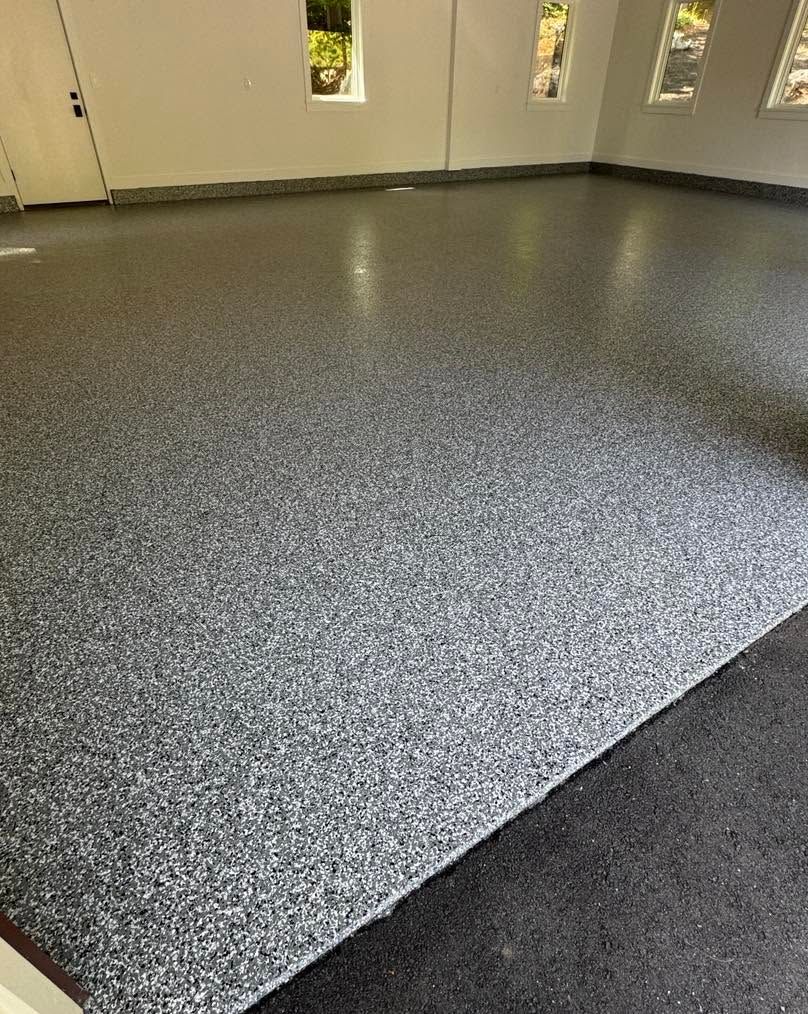 Empty room with speckled gray epoxy floor and beige walls with narrow windows