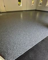 Empty room with speckled gray epoxy floor and beige walls with narrow windows