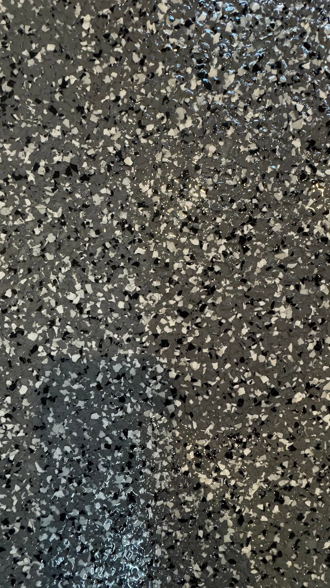 Speckled gray and black textured surface with a faint bluish patch near the bottom left