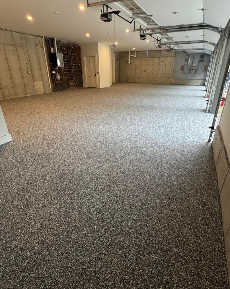 Empty carpeted garage interior with overhead lights and open garage doorers