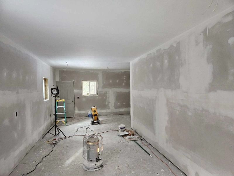 Room under construction; drywall installation with partially finished walls, ceiling. A work light and heater are present.