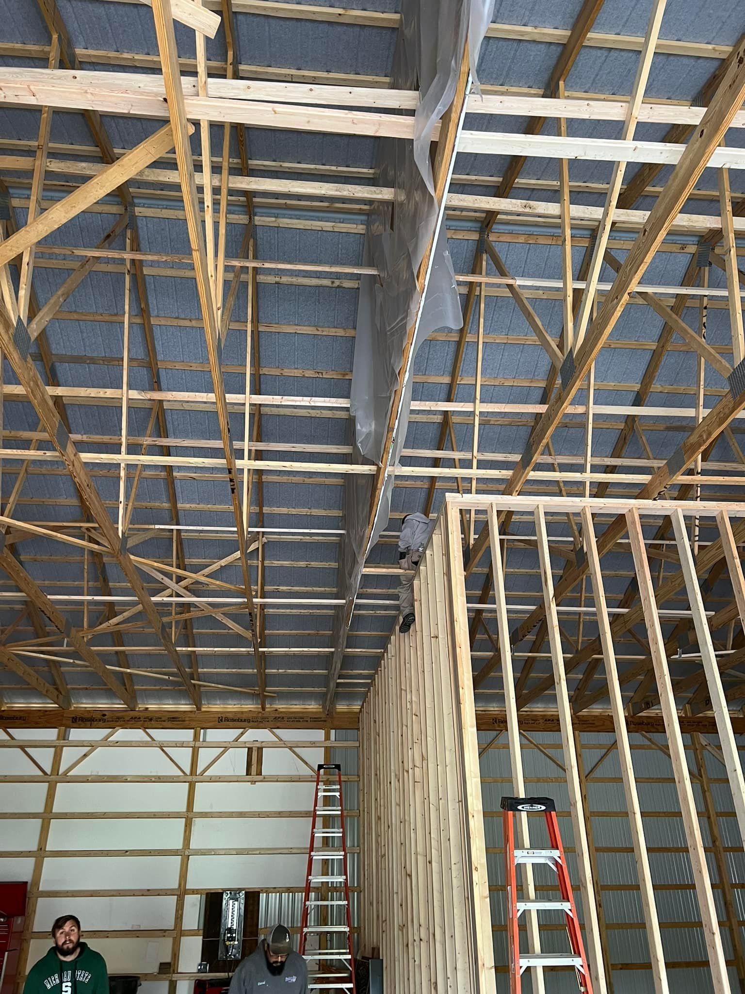 Construction workers inside a building under construction, working on the wooden framework and roof.
