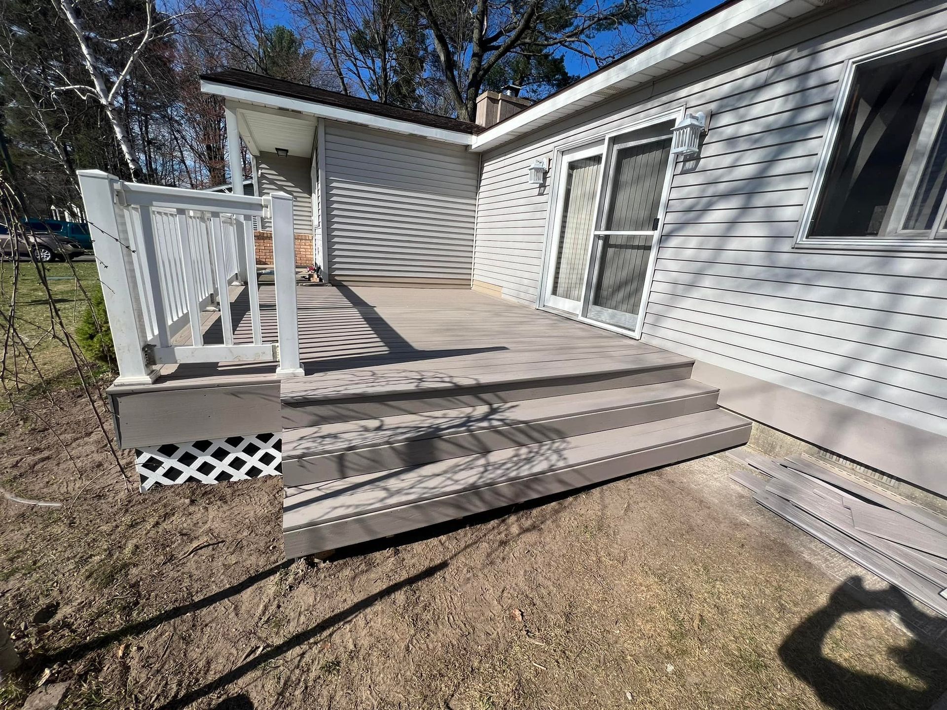 Dirt pile in foreground, grassy area near water, trees and blue sky.