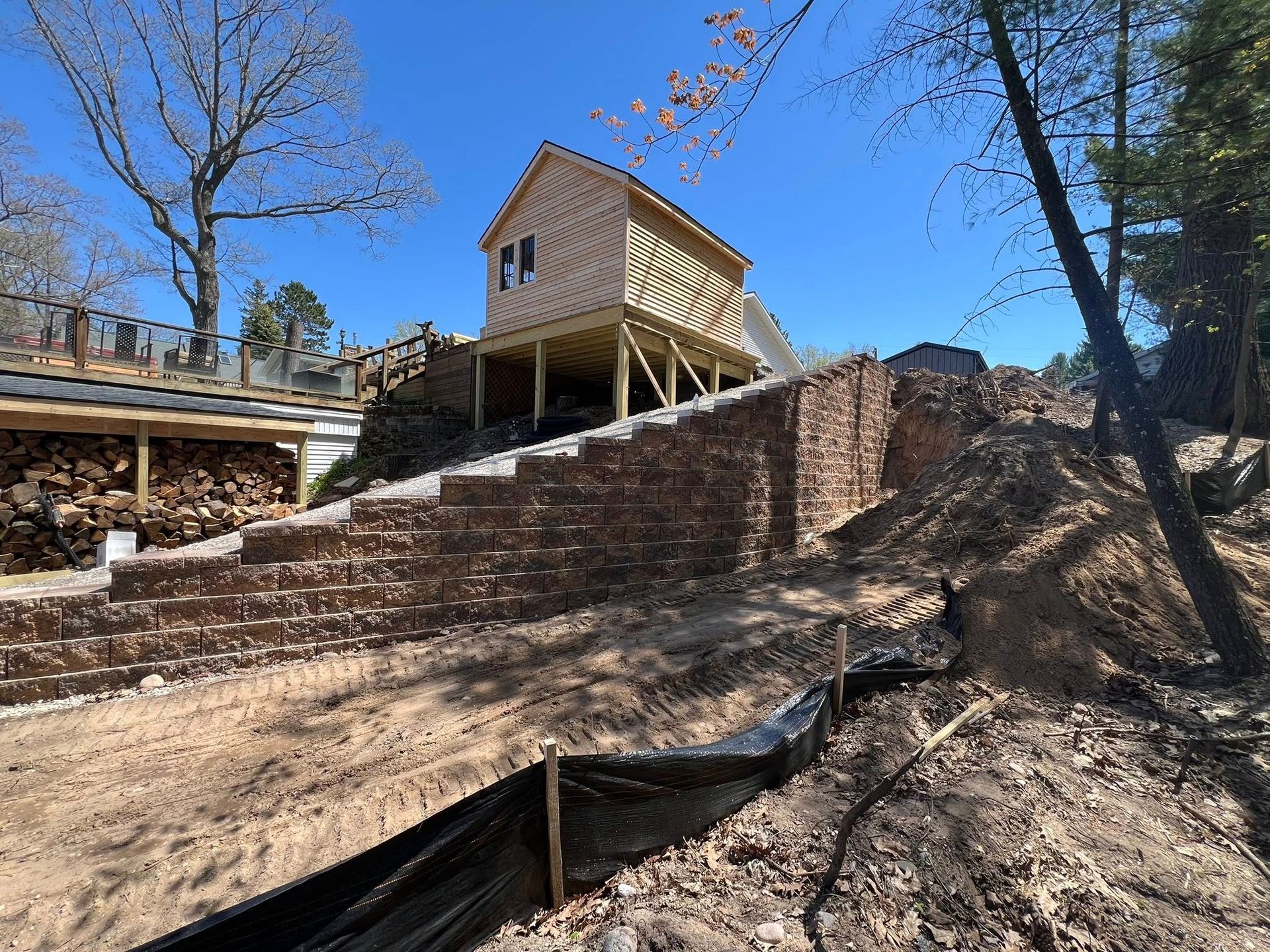 Wooden structure being built on a tiered brick retaining wall. A dirt slope is in the foreground.