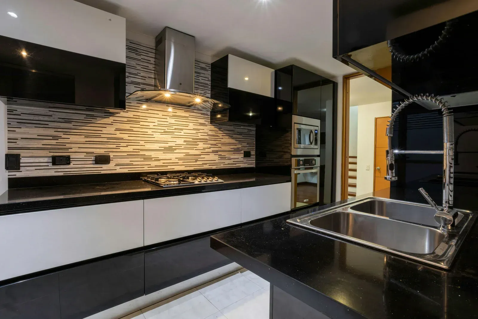 Modern kitchen with black countertops, white cabinets, and stainless steel appliances.