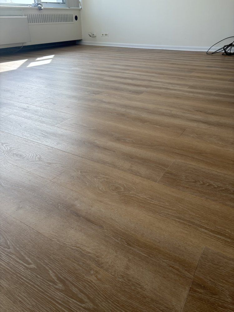 Empty room with wood-look flooring. Window and radiator on the left.