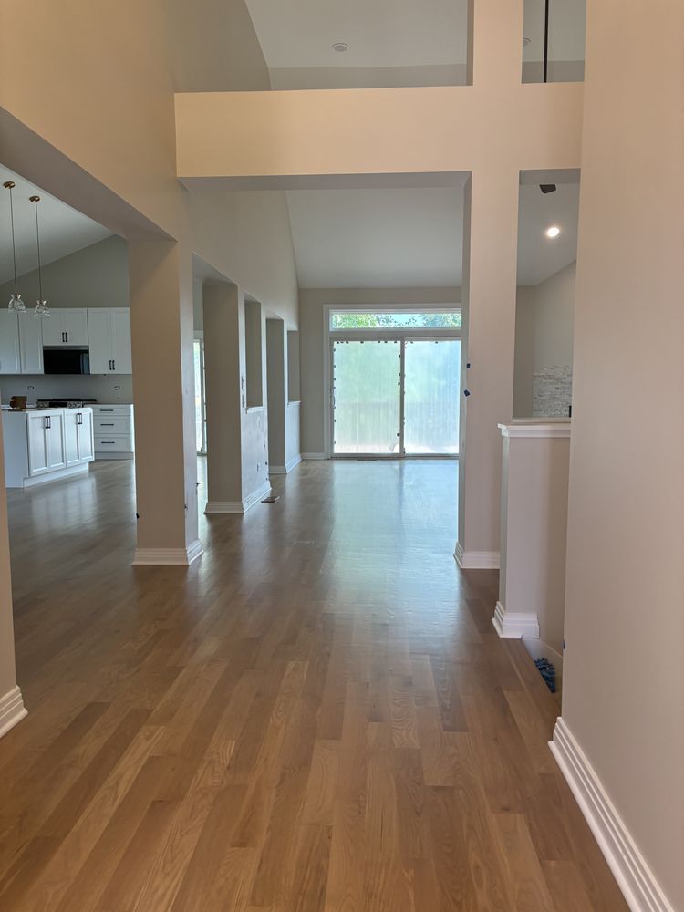 Entryway with light wood floor, neutral walls, leading to living room with sliding glass door. Kitchen visible on the left.
