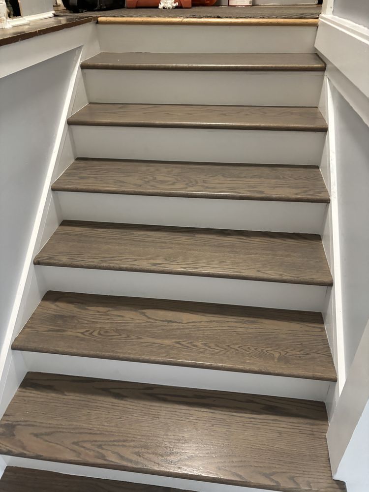 Wooden stairs with gray treads and white risers, ascending towards a landing, with light strips on sides.
