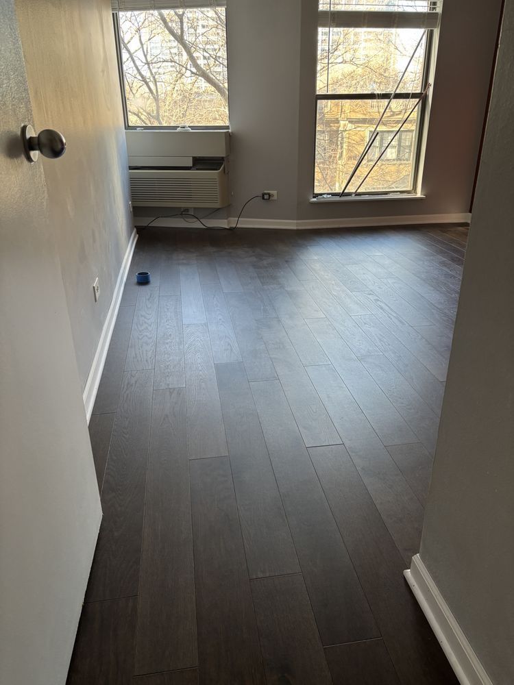 Dark wood floor in a room with two windows, a door, and a wall-mounted AC unit.