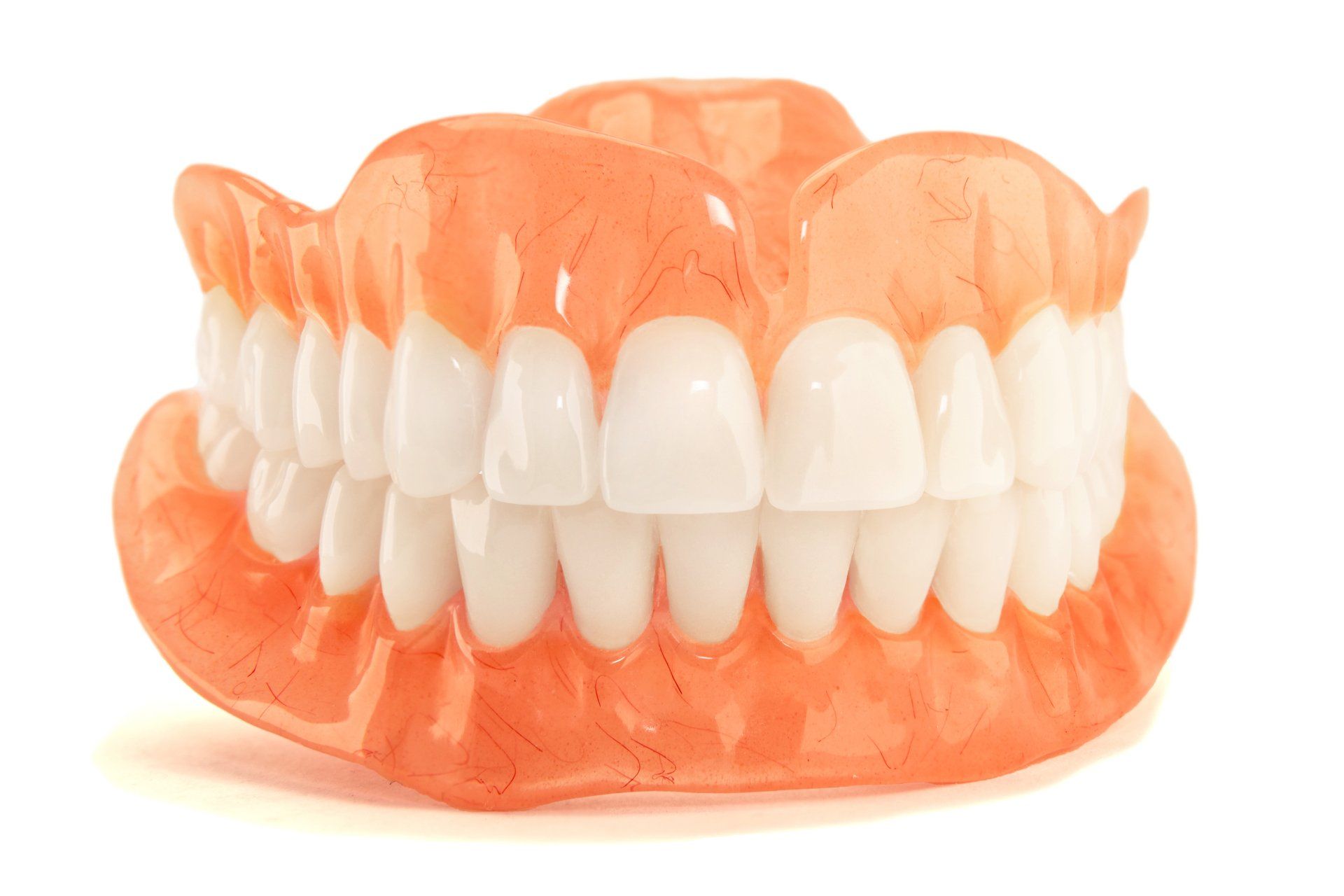 Dentures, upper and lower sets, with white teeth and pink gums, against a white background.